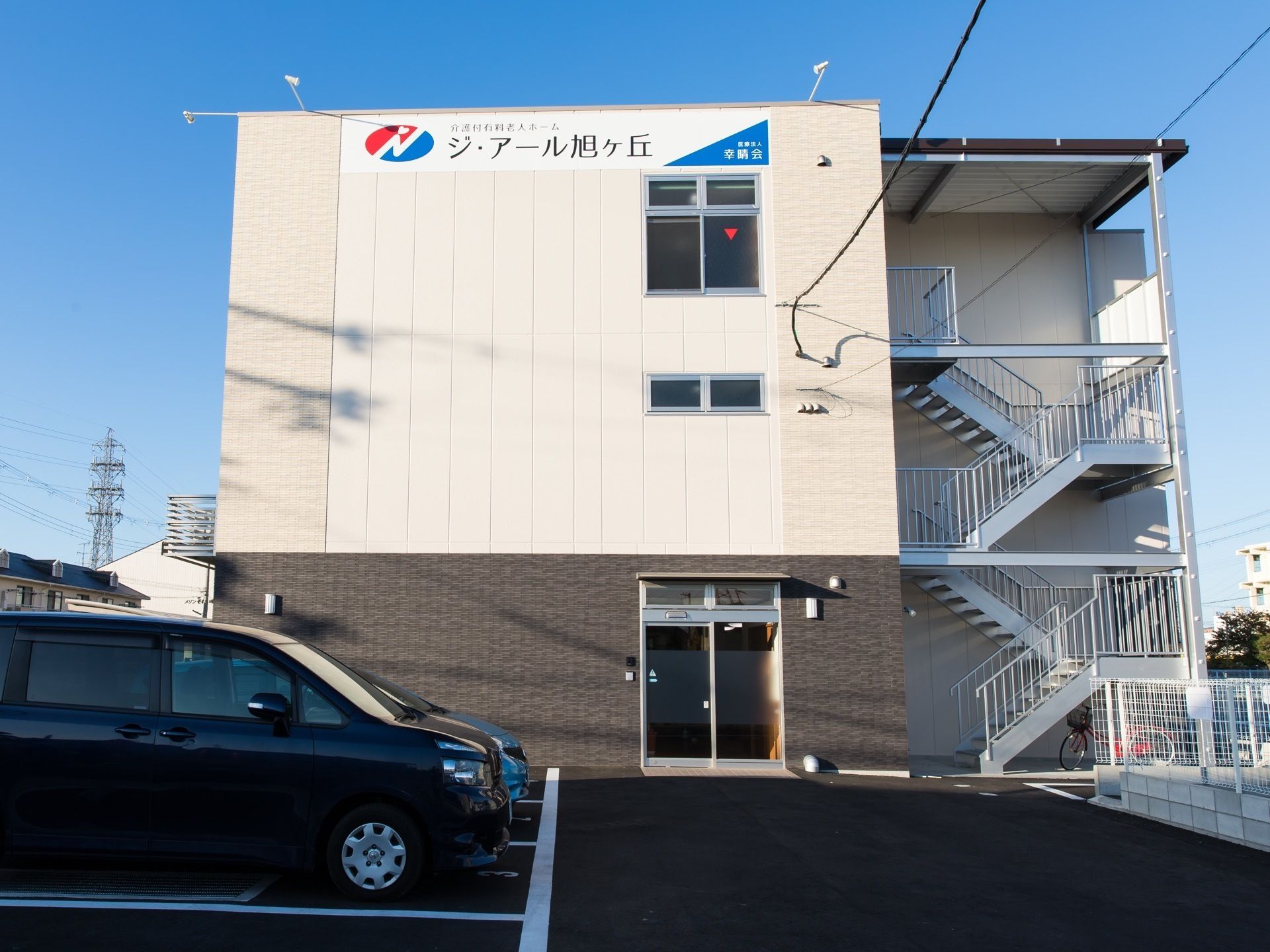 １階部分が茶色、２階以上が白色を基調とした外壁の３階建ての施設である。３階から敷地面まで手すりがついた外階段が設置されている。