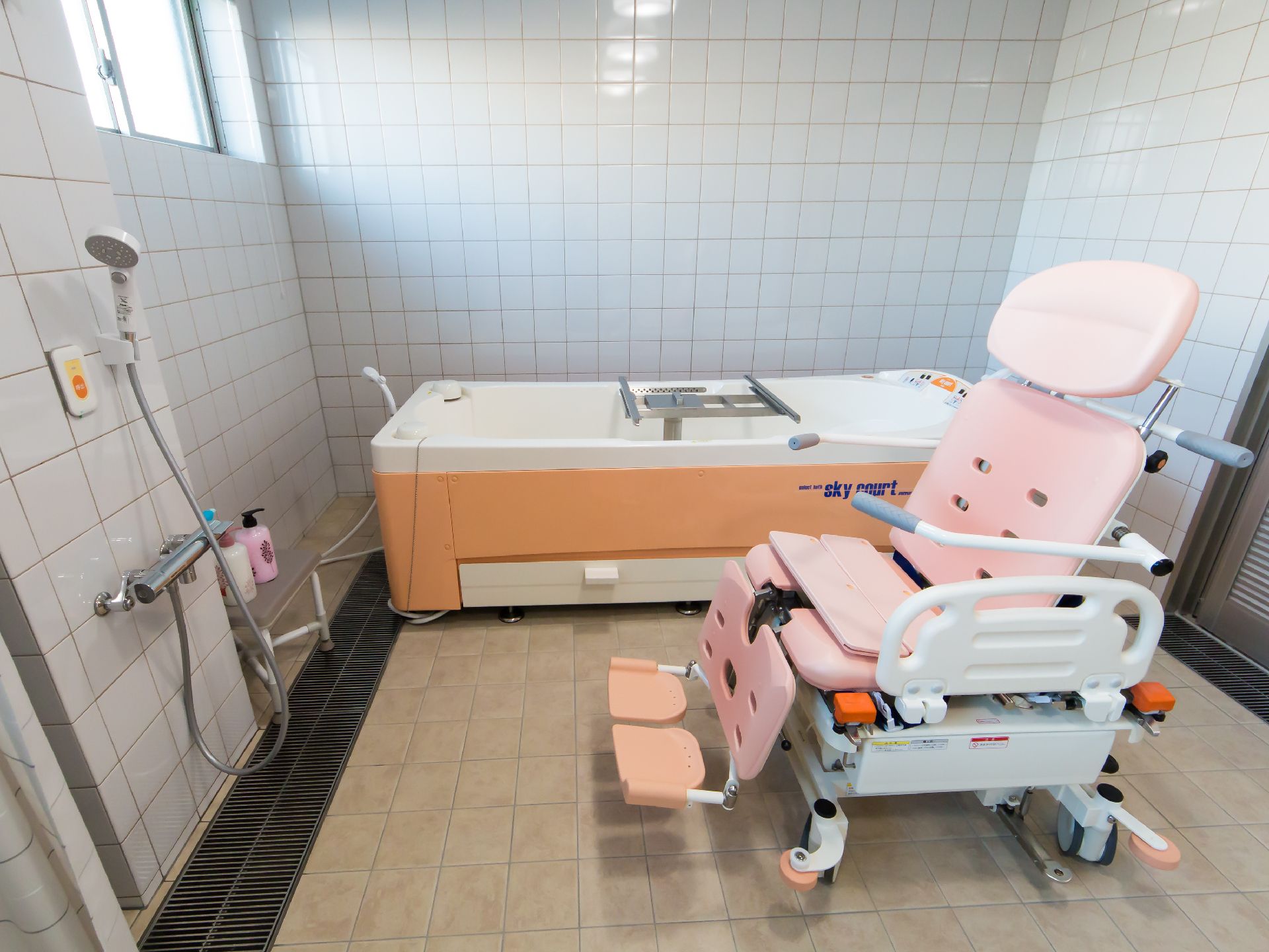 介護浴槽とシャワーチェアが完備され、左の壁にはナースコールが設置されている浴室