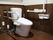 ゆとりのある広さのトイレがある。床はフローリングが敷かれ、便座の横や壁には手すりがある。