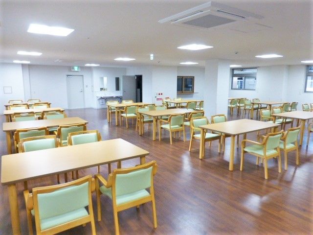 食堂には4人掛けのダイニングテーブルが多く並べられ、車いすなどが通るスペースも確保されている。