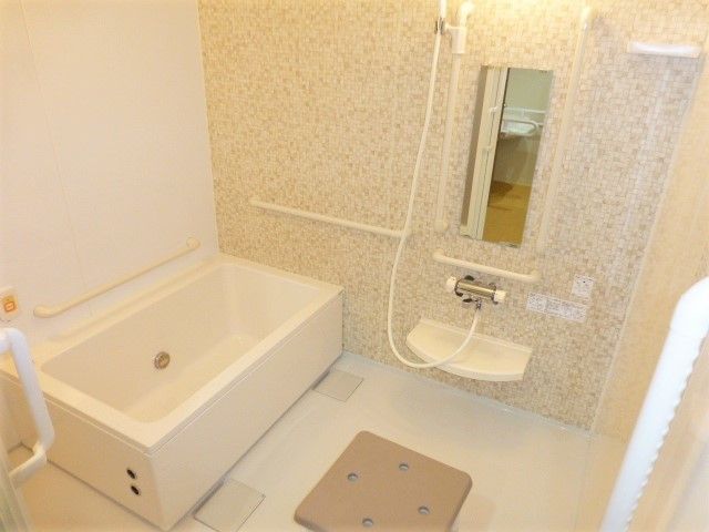 白い浴槽が置かれた広い浴室は洗い場がゆったりとしていて、シャワーや手すりも設置されている。