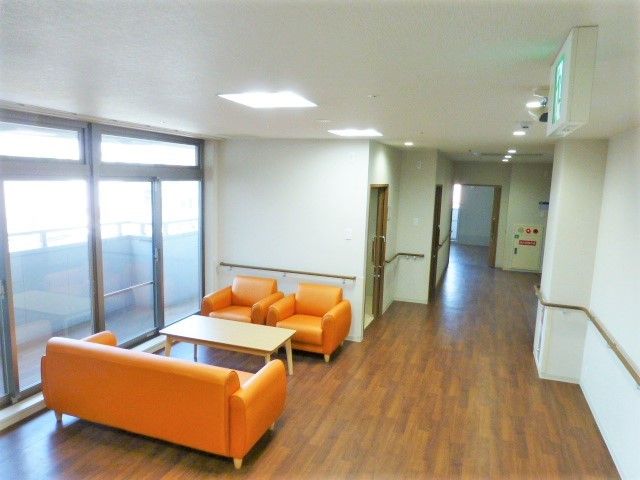 オレンジ色のソファが対面式に並べられ、廊下には手すりが付いている。