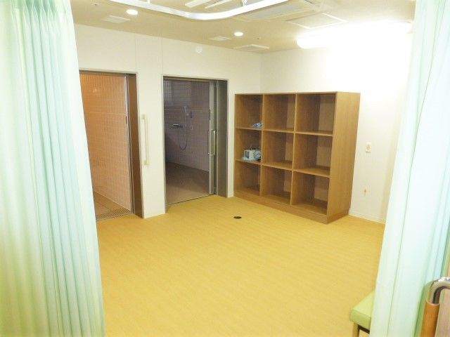 ペールグリーンのカーテンで仕切られた部屋。奥には木製の棚が置いてある。
