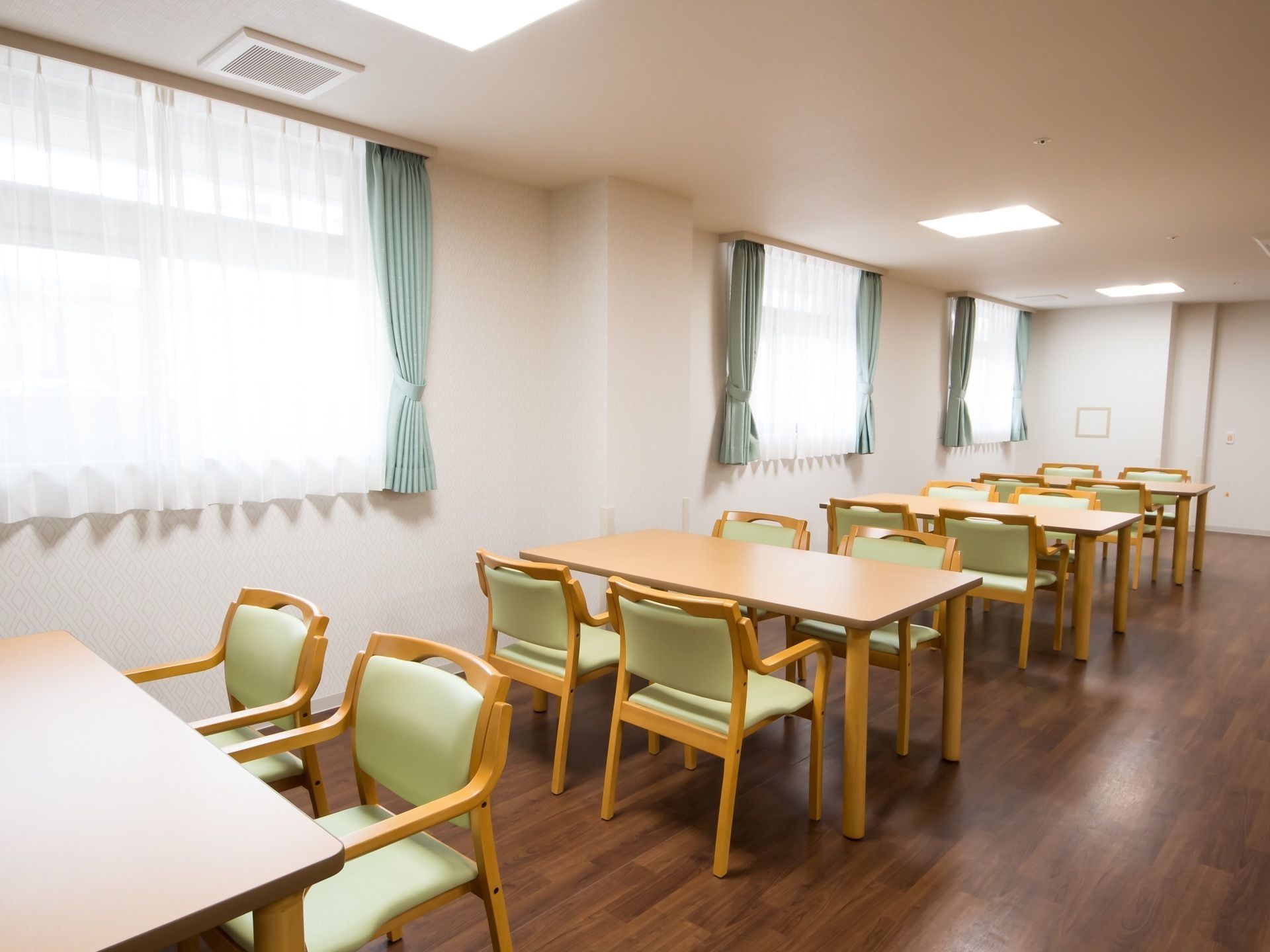 テーブルと椅子がいくつも置かれている。窓にはカーテンが掛けられており、床はフローリングになっている。