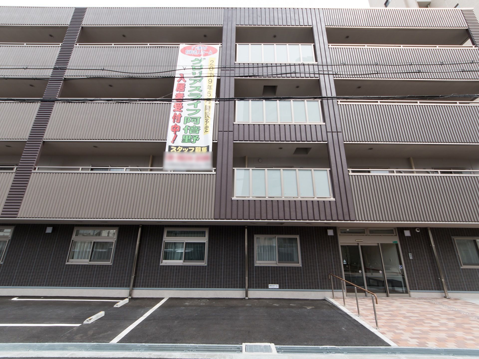 シックなグレーで施されたマンション風の建物である。敷地内には駐車スペースが設けられている。入り口は自動扉になっている。