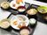 3種類の食事がそれぞれ異なるトレーに並べられている。丼物や肉料理をメインにした食事など。