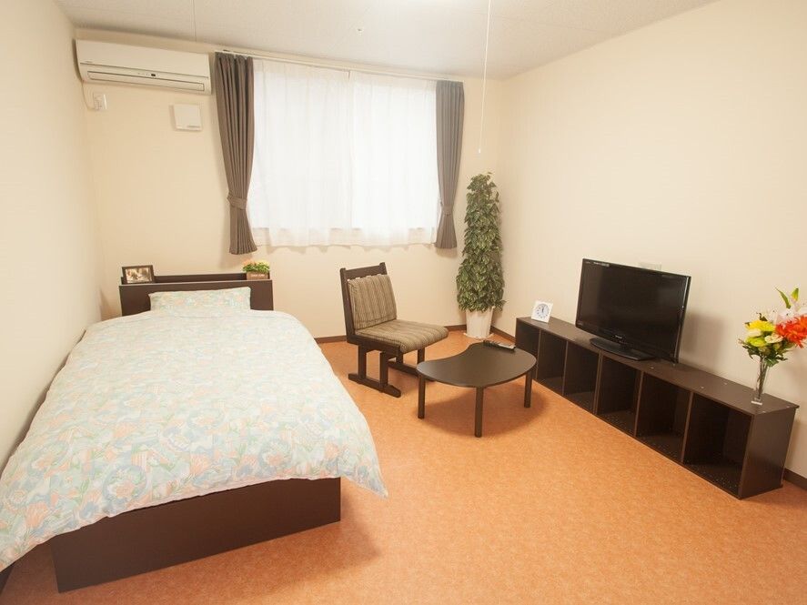 エアコンが付いた個室の部屋には寝具付きのベッドやテレビが置かれ、花や観葉植物が飾られている。