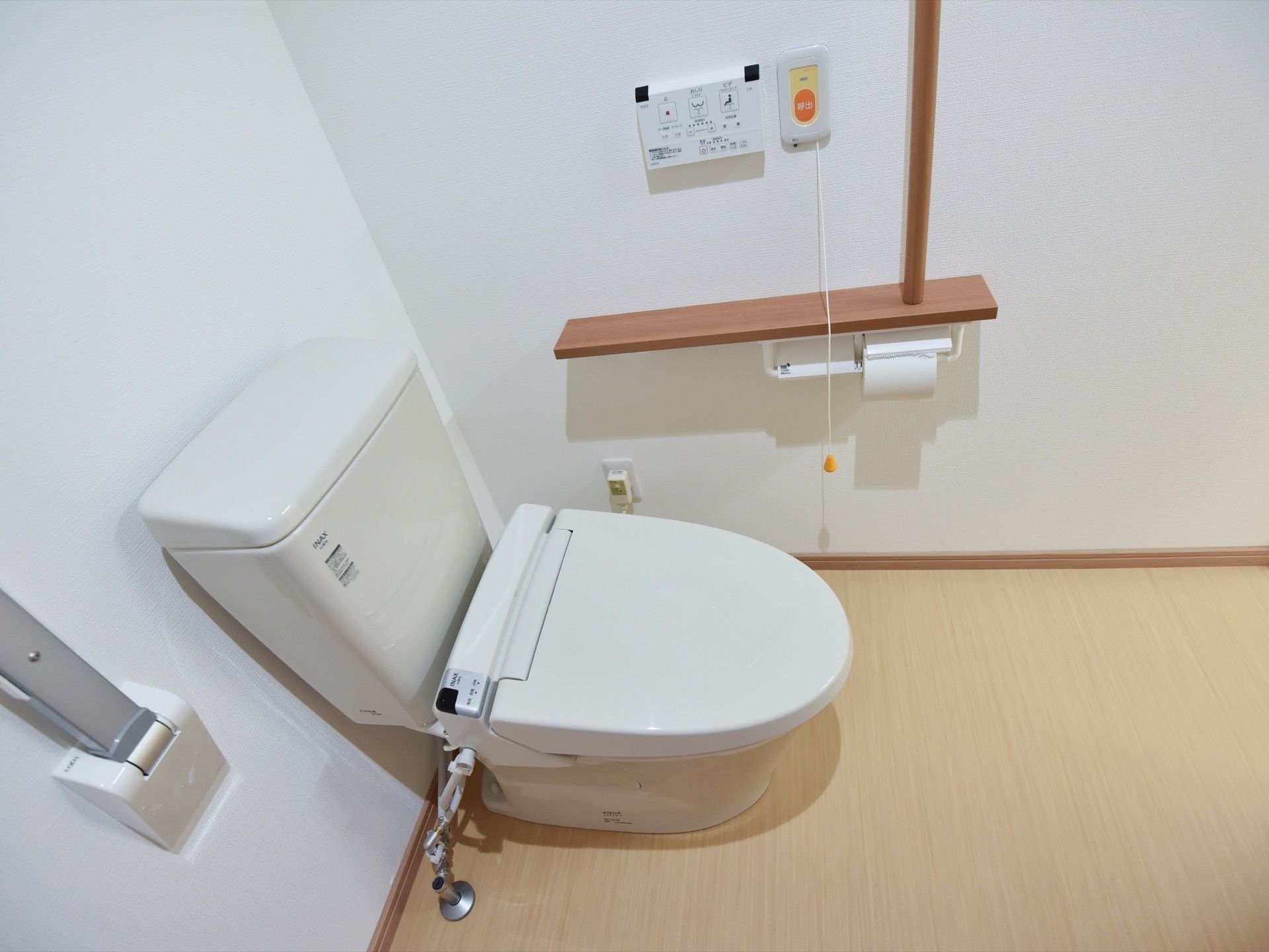 トイレの個室は、白い内装で明るく清潔感があり、利用しやすい雰囲気になっている。温水洗浄便座のそばに、安全バーや手すりが設置されている。