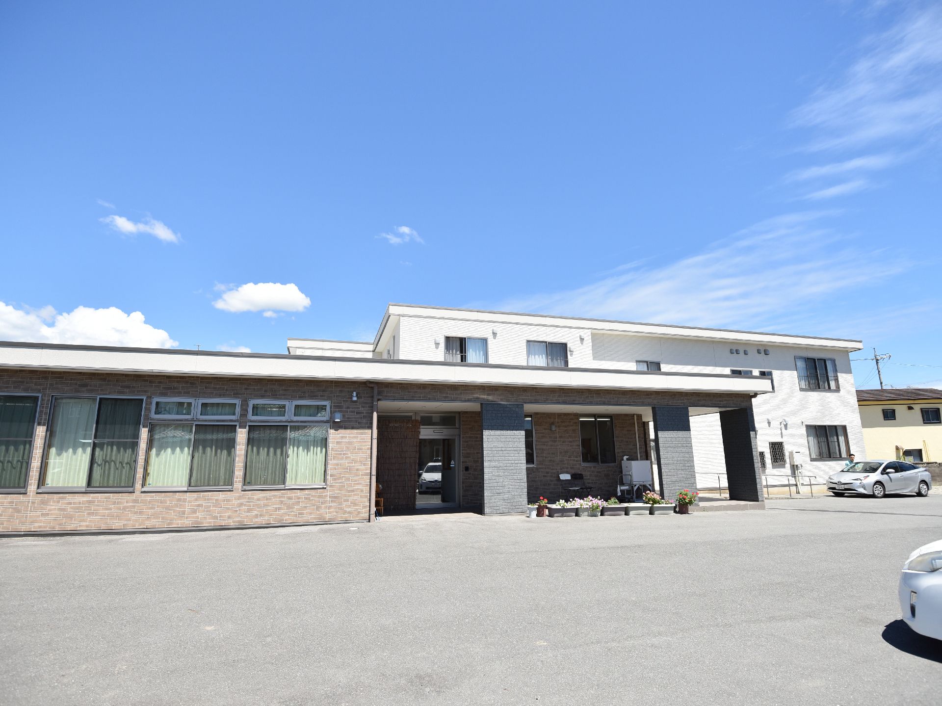 多くの駐車スペースがある、一階建てと二階建ての2つの棟からなる施設