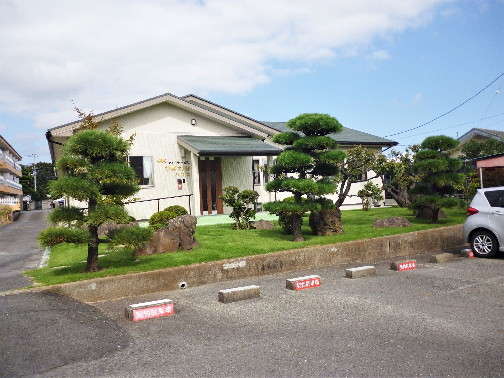 三角屋根が付いた平屋建ての建物の玄関には手すり付きのスロープがつき、外壁にはホーム名が書かれている。