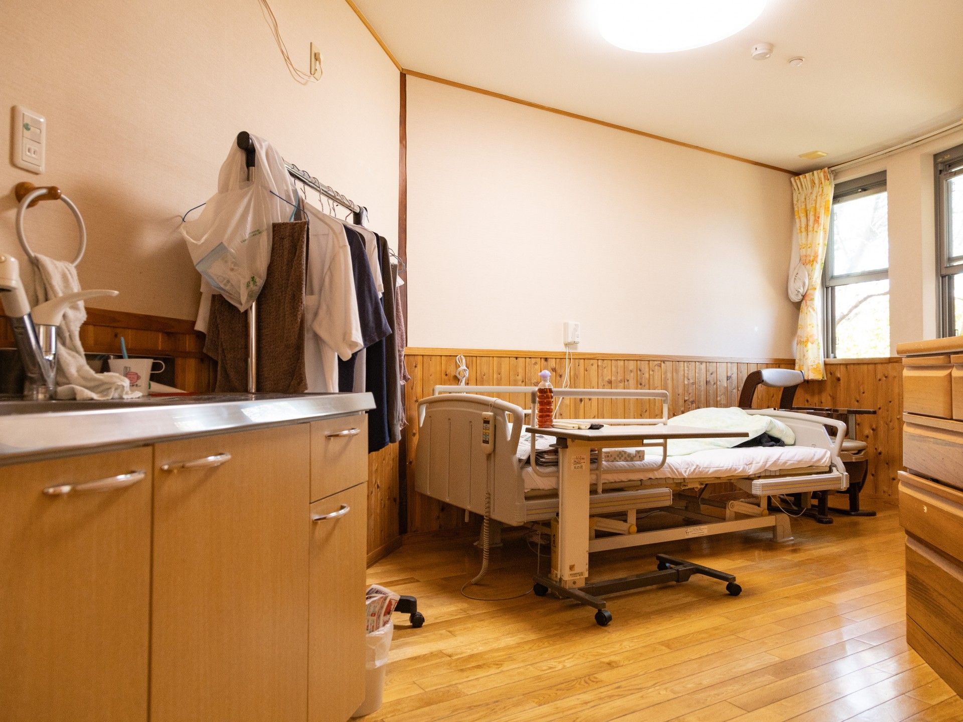 患者のケアをする看護師・介護士とベッドに横たわる高齢者。介護している写真