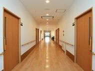 手すり付きの廊下には居室のドアが並んで設置され、奥の突き当りには大きな窓が付き、廊下の壁には防災設備もある。