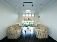 花柄のソファが置かれた談話スペース。二つのソファの中央にはローテーブルが置かれ、窓からは陽の光が入っている。