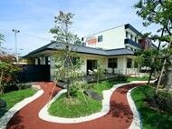 大小の木が植えられた庭には白枠で囲われたエンジ色の遊歩道があり、建物の周りを歩くことができるようになっている。