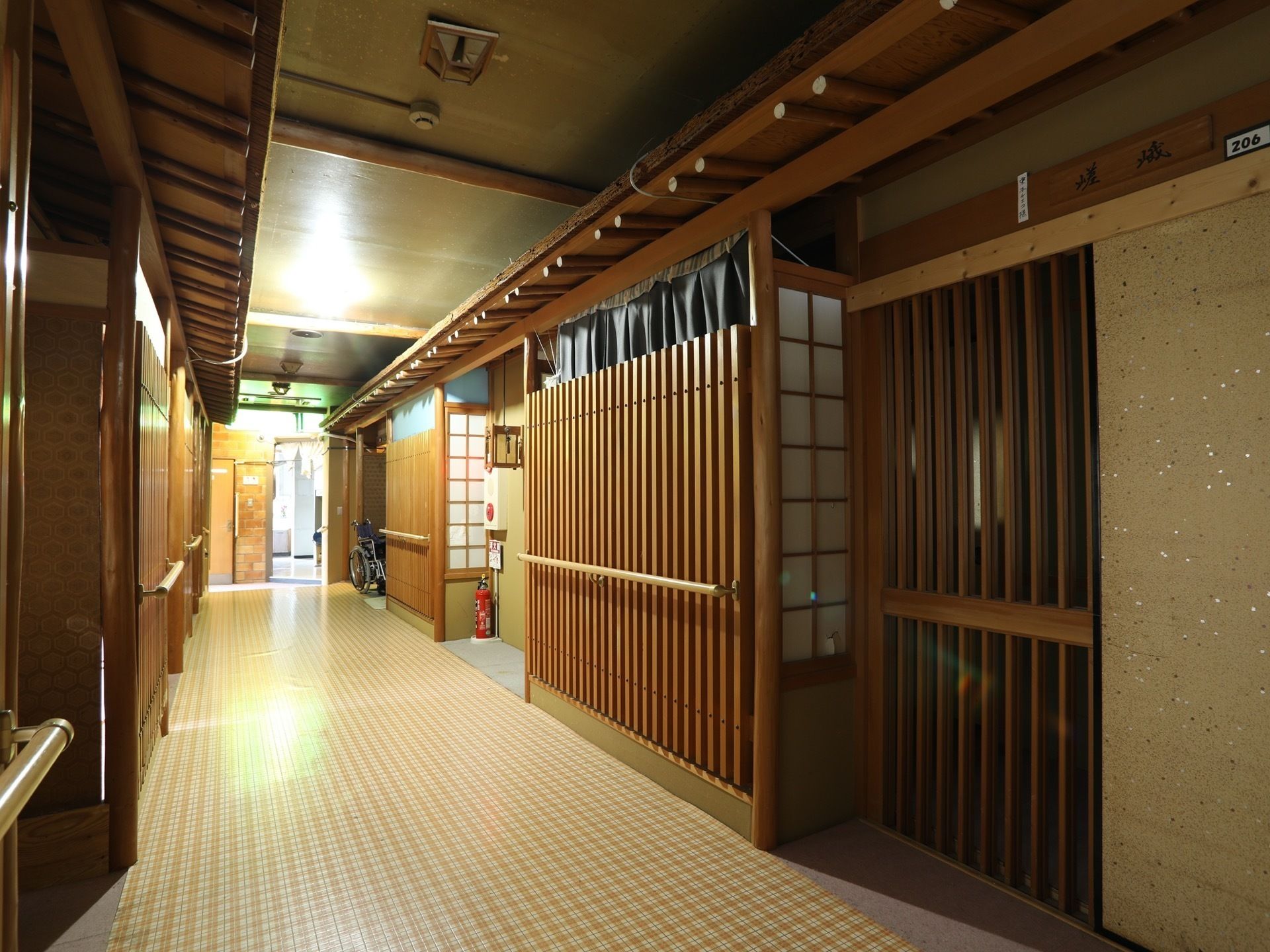 廊下は旅情気分を味わえる日本家屋風になっている。壁には緊急時に備えた非常ボタンと消火器を配置している。