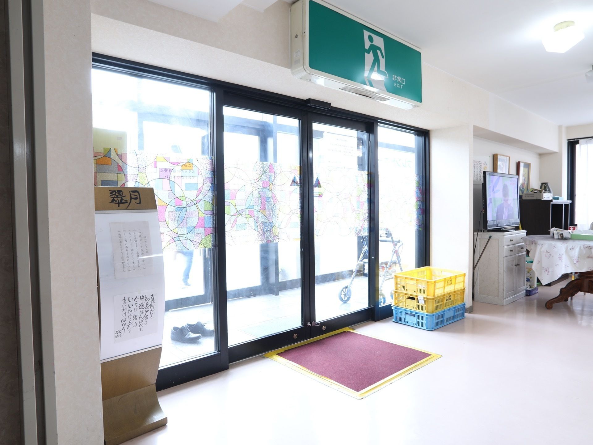 扉は二重ガラスの自動ドアになっていて明るくなっている。足元は凹凸がない。扉の上には大きな非常口の案内がある。