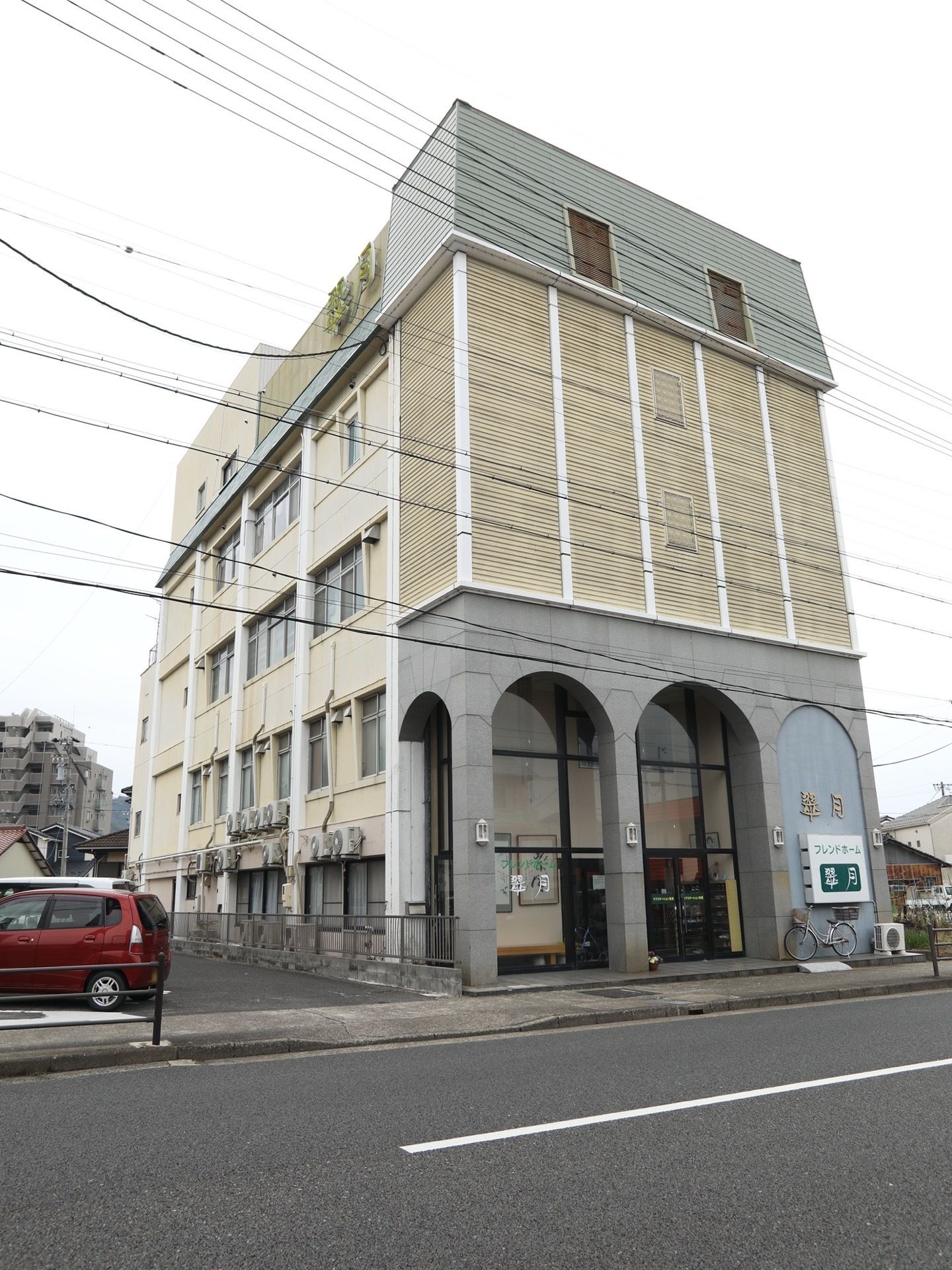 施設は地上４階建てで壁には大きく施設名が入った看板が掲げられている。整備された大きな道路に面して建っている。