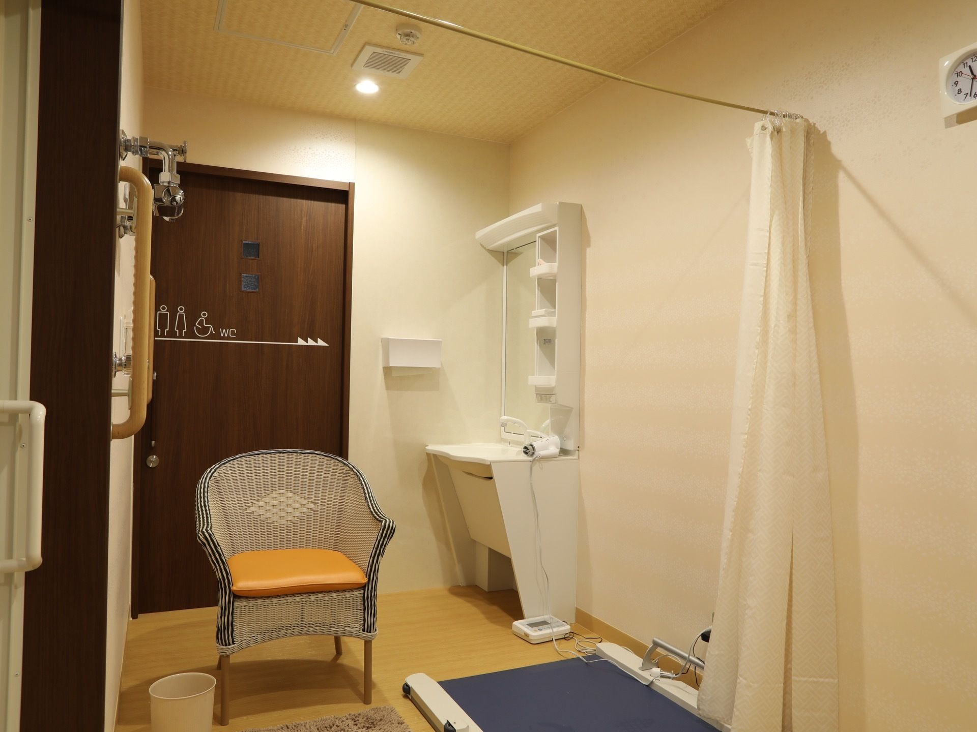 トイレのドアの横には洗面台がある。そのほかに、椅子やカーテンが取り付けられ、足元に機材が置かれている。