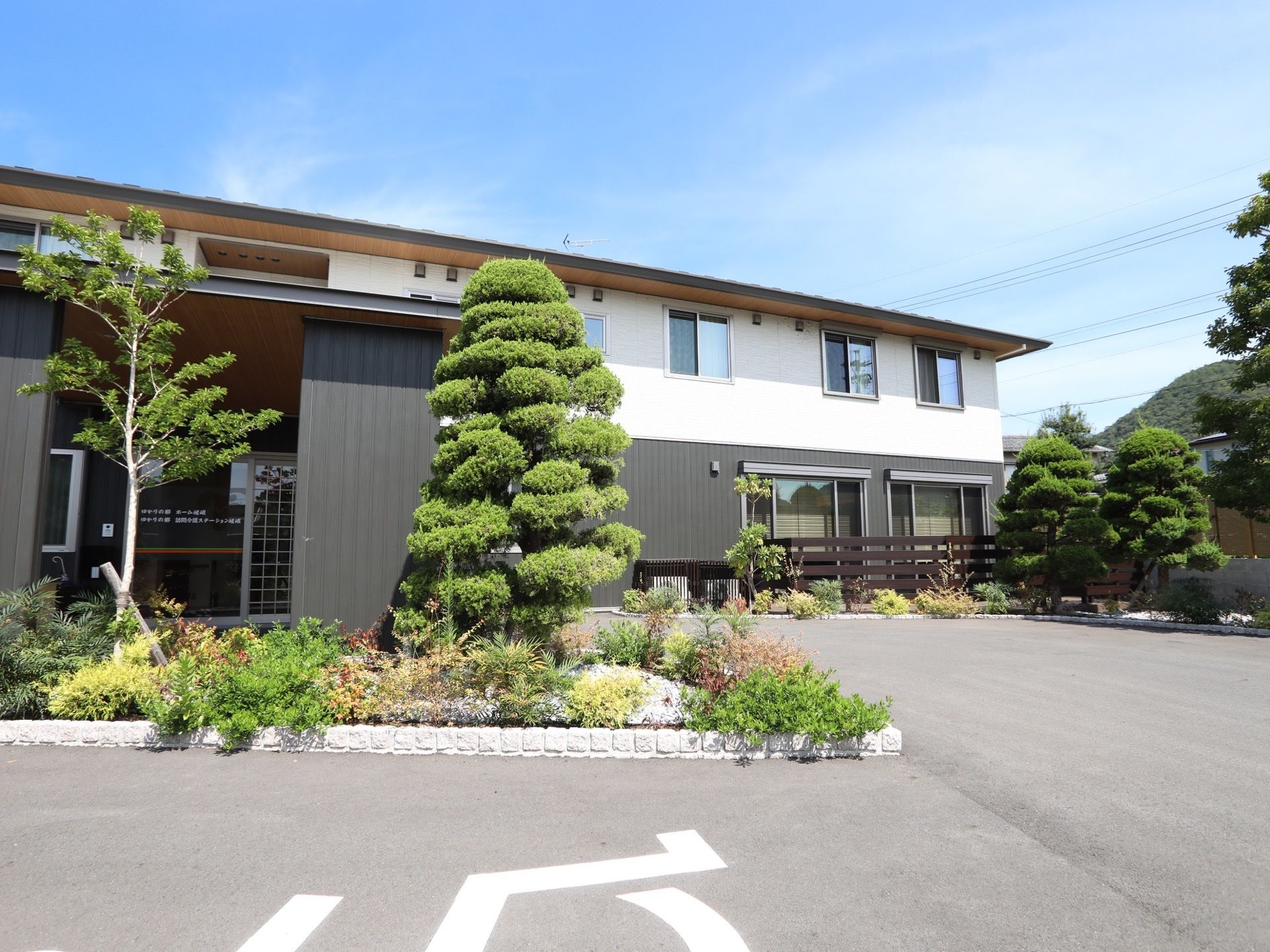 舗装された敷地があり、豊かな植栽に囲まれた住宅が建っている。周囲には背の高い建物がなく、開放的な環境である。