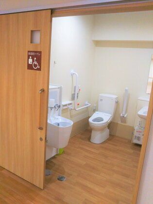 広いトイレはオストメイト対応の仕様で段差がなく、トイレの両サイドに手すりがあり、呼び出しボタンも設置されている。