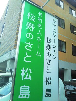 緑と白の看板。緑の背景に白の文字でホーム名が書かれ、白の背景に黒い文字で併設事業所名が書かれている。
