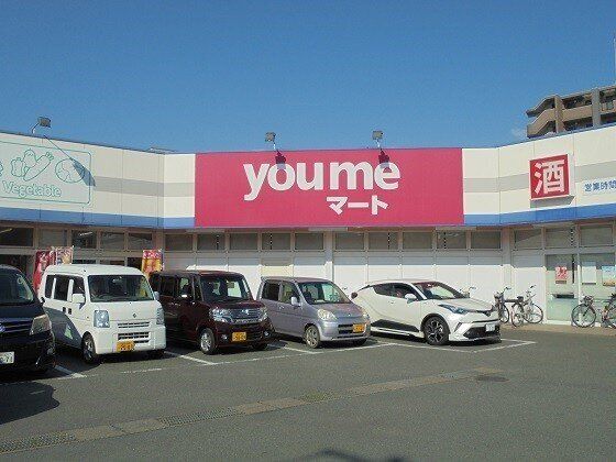 たくさんの車や自転車が店の前に止められたスーパーマーケット。「酒」の文字も書かれている。