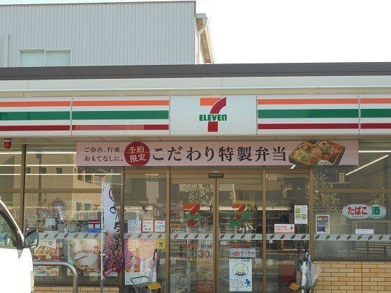 コンビニエンスストアの前には駐車場があり、「酒・たばこ」の文字も書かれている。