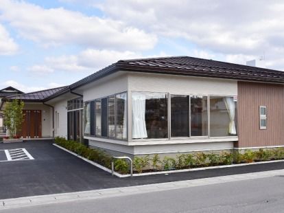 広い駐車場が付いた平屋建ての建物の周りには木や花も植えられ、アットホームな雰囲気。