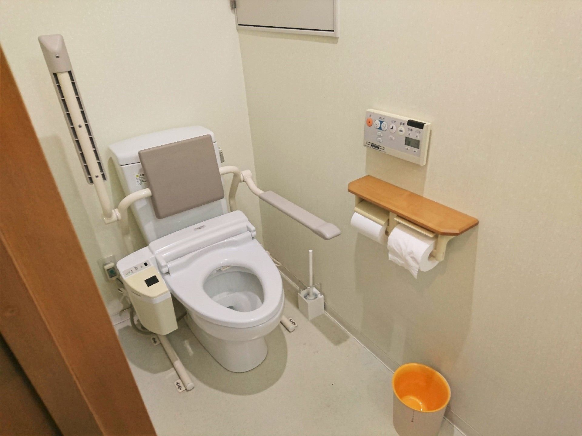 背もたれや可動式の手すりが設置されたトイレ内は広く、ごみ箱なども置かれている。