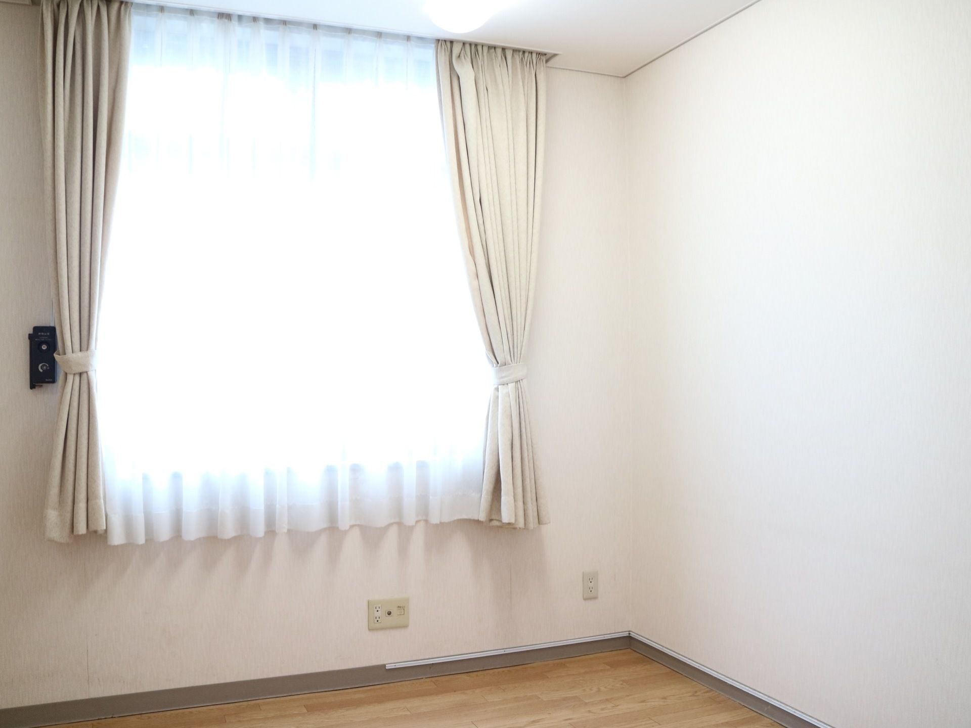 窓から自然光が差し込む明るい居室である。壁にコンセントが完備されており、床はフローリングになっている。
