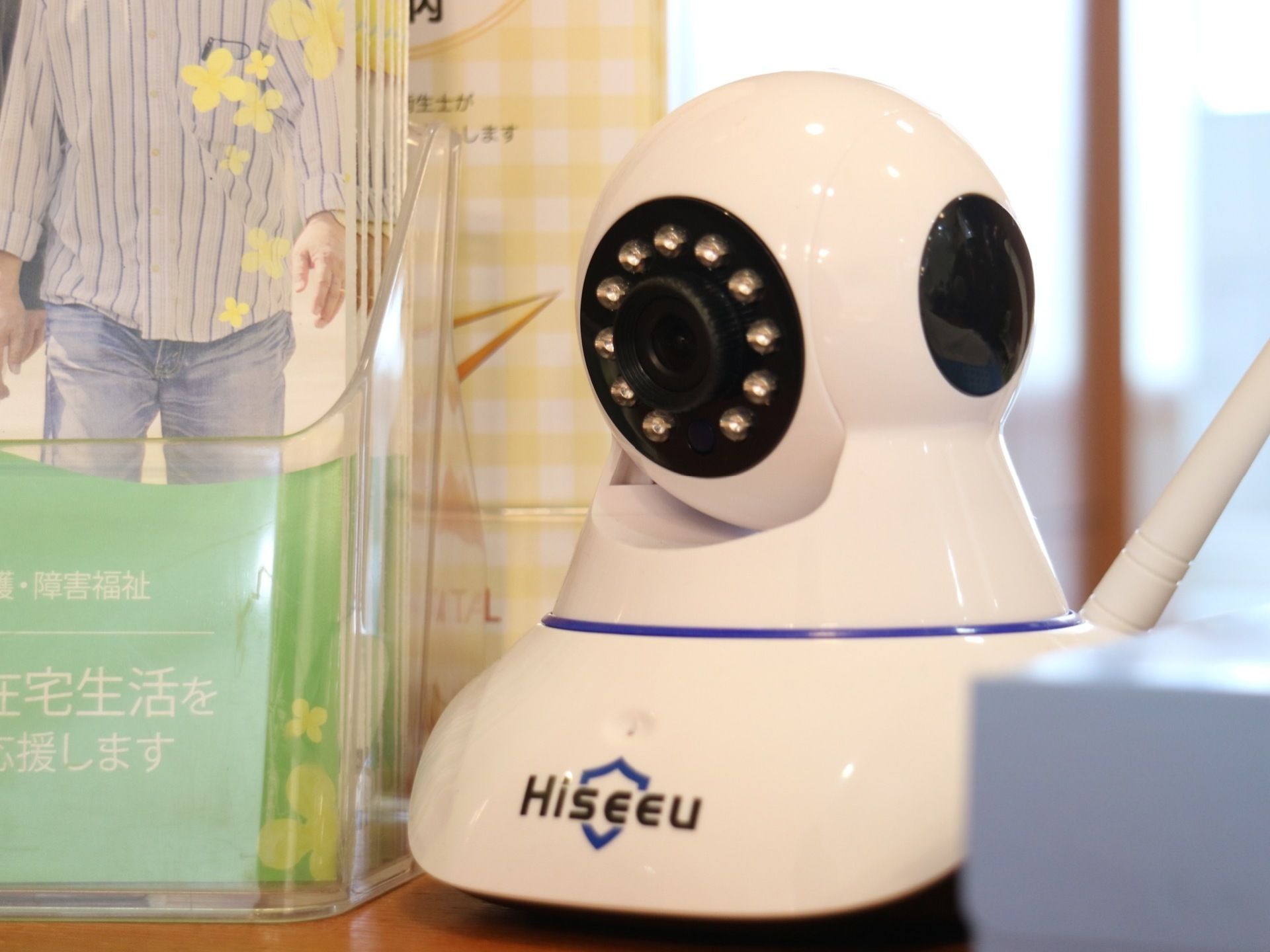 ネットワークカメラが受付カウンターの上に設置されている。施設のパンフレットや箱ティシュも置かれている。