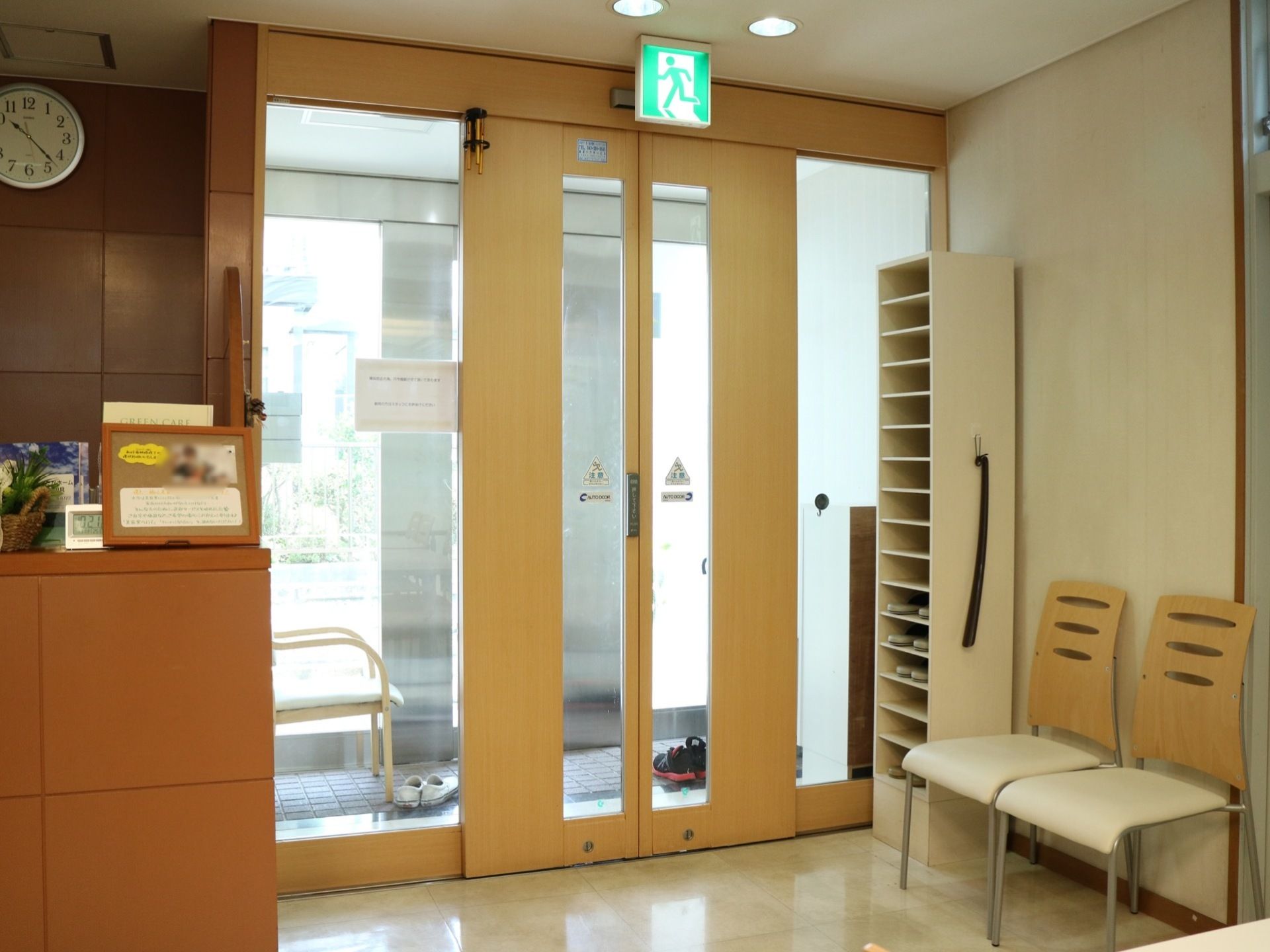 玄関には、タッチ式自動ドアが設置されている。左に受付が設けられており、右の壁際に椅子とスリッパラックが置かれている。