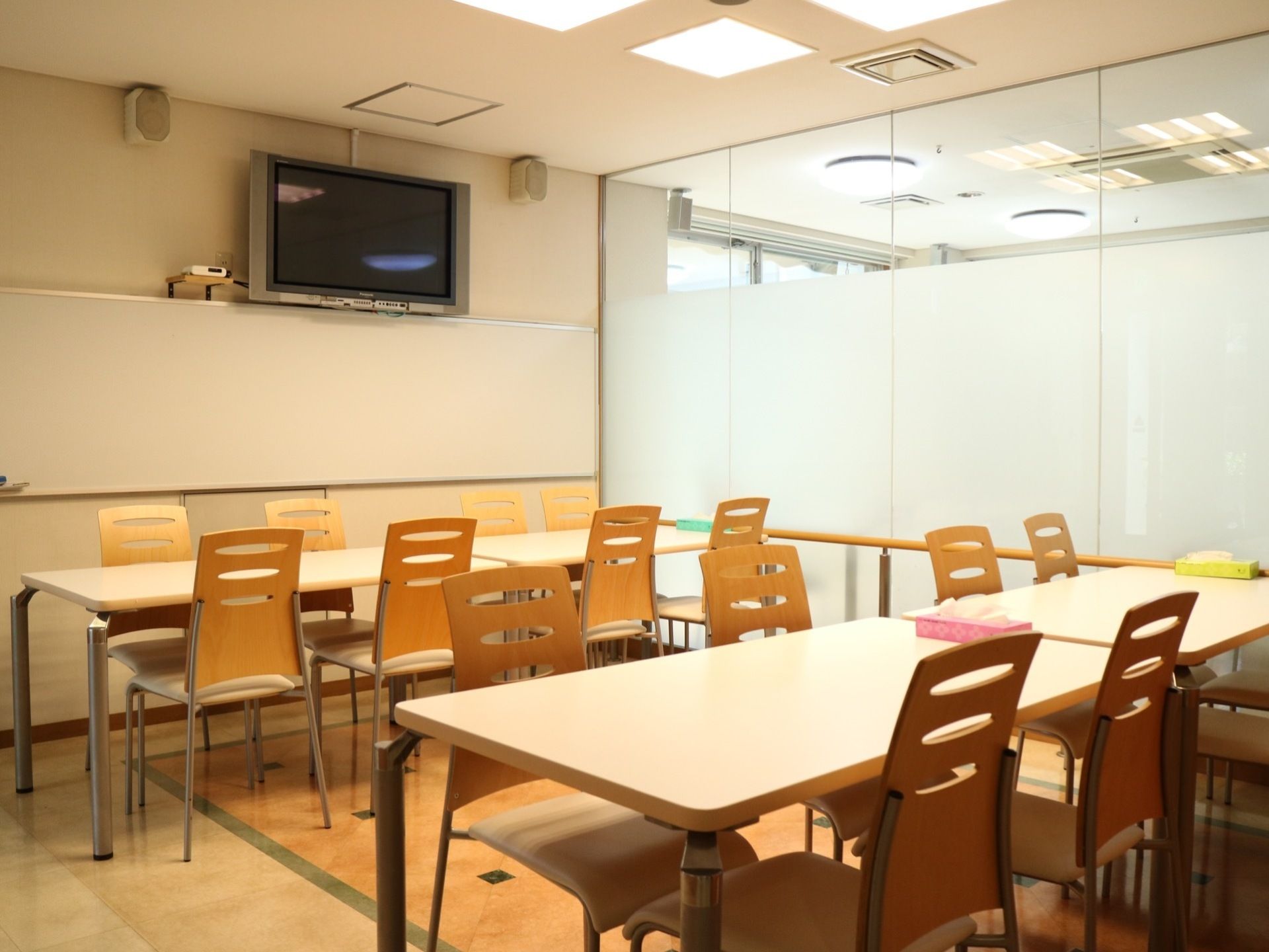 明るく開放的な食堂である。４人掛けテーブルが４つ並べ置かれている。壁にスピーカーとテレビが設置されている。