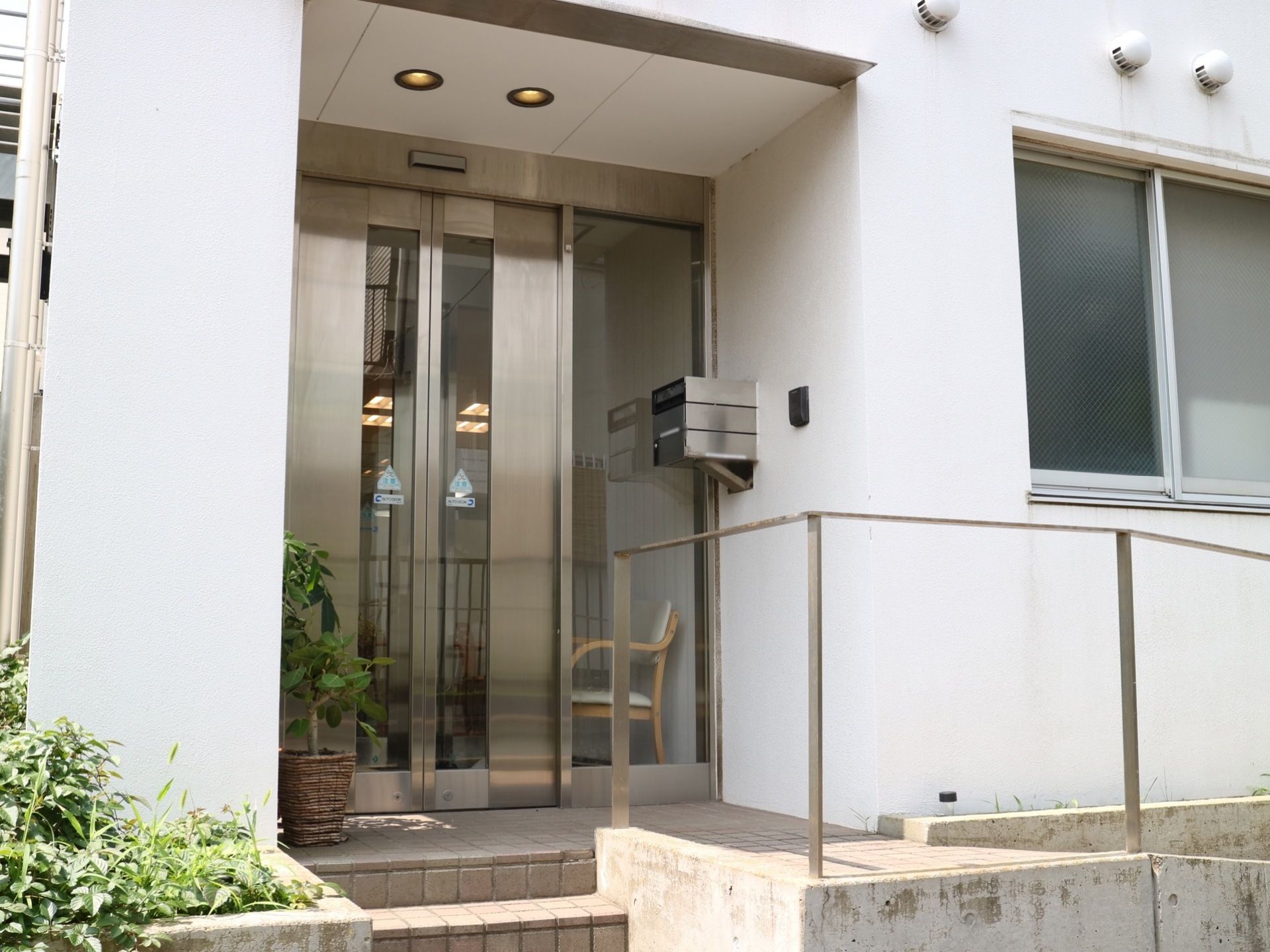エントランスには、手すり付きのスロープが設けられている。郵便受けとインターホンが壁に設置されており、自動ドアが玄関扉として採用されている。