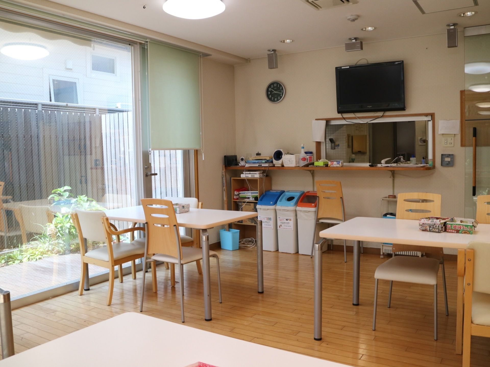 対面式キッチンが併設された食堂である。カウンターの下には、分別用ゴミ箱やカラーボックスが置かれている。