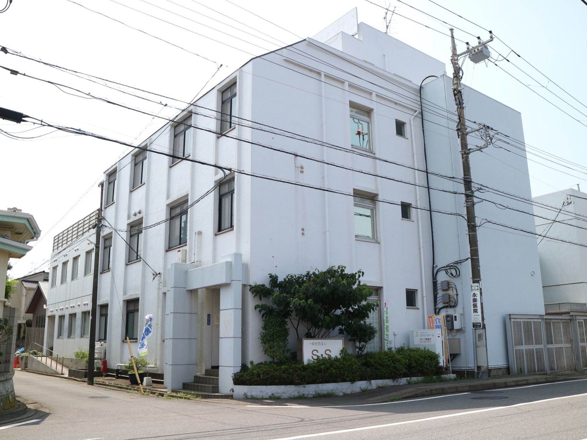 白い外壁が特徴の３建ての施設である。正面玄関の他に救急用出入り口が設けられている。スロープが玄関アプローチに設けられている。