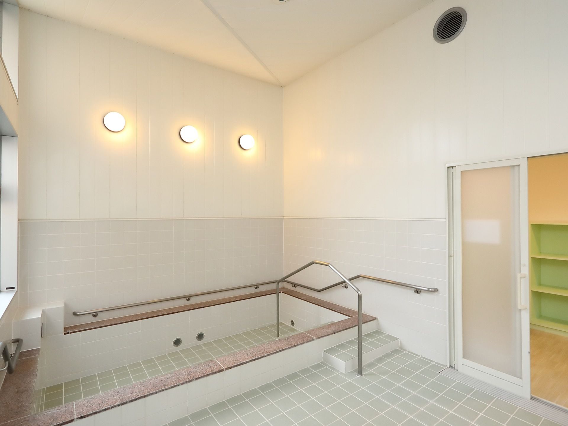 天井の高い広々としたタイル張りの浴室。大浴槽の周囲には、ステンレス製の手すりが設置されており、安全に使用することができる。