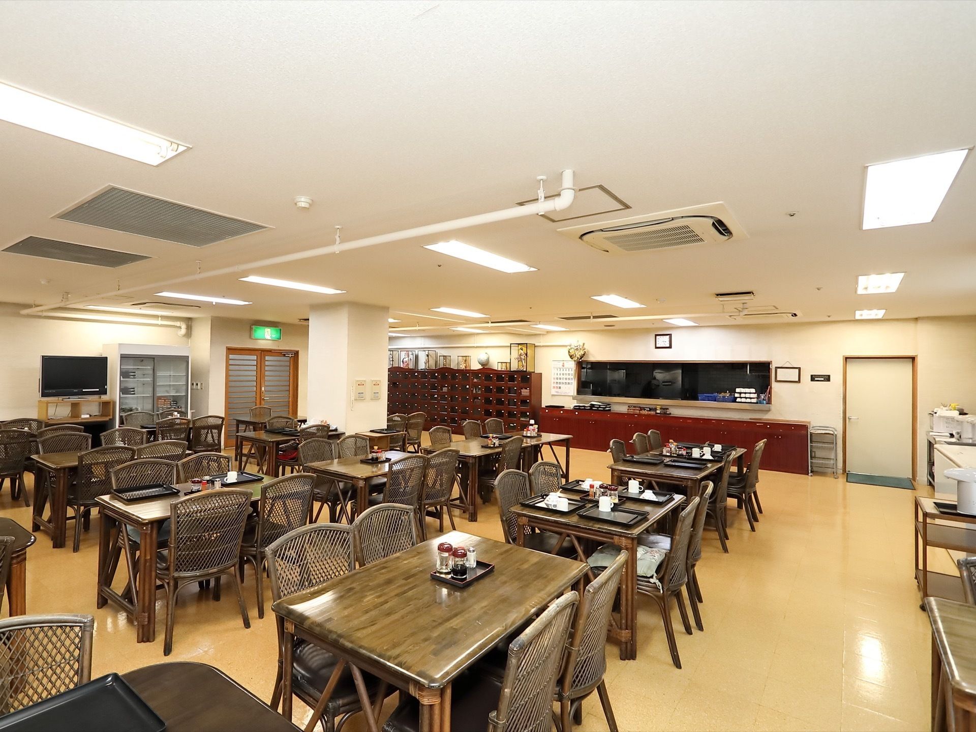 広々とした室内に、焦茶色のダイニングセットが整然と並べられている。出入り口側の壁際に、液晶テレビがある。