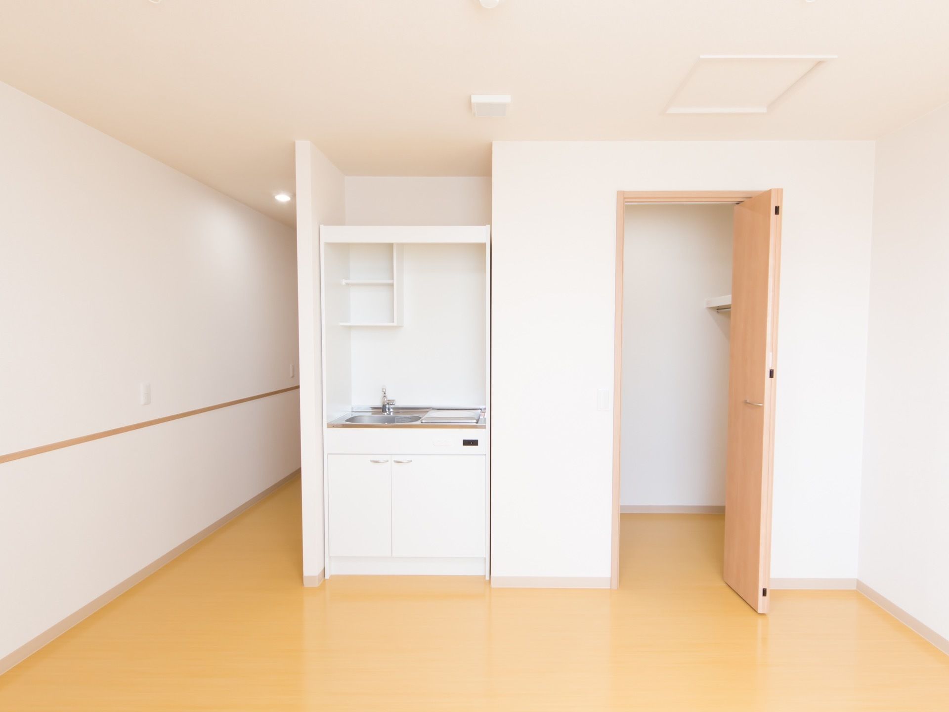壁紙は白で、フローリングや扉は木目の居室である。ワンルームで、広さも確保されている。明るいお部屋である。
