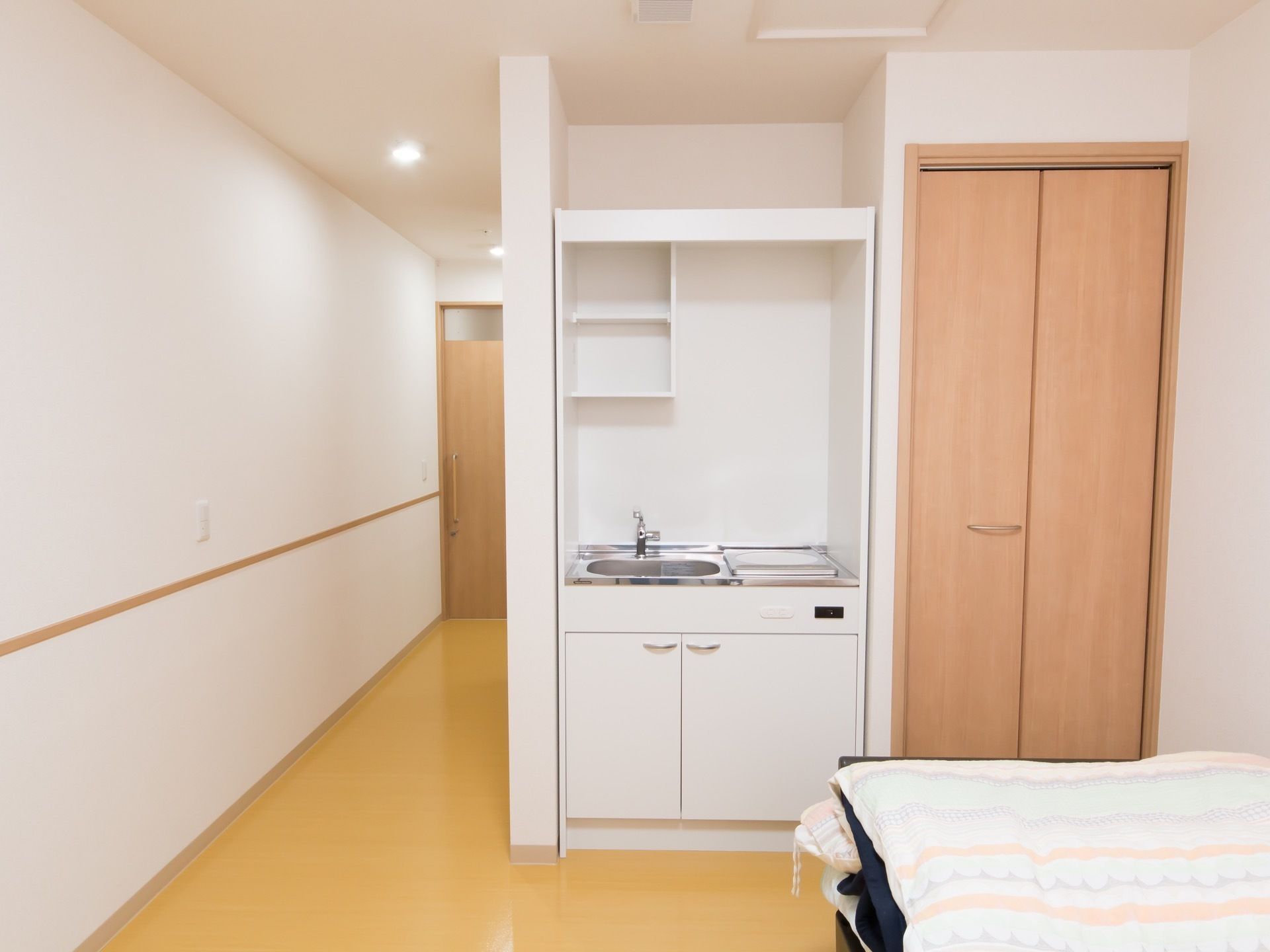 居室内にミニキッチンが建てつけられている。流しに、安全に使用できる電気調理器具が取りつけられている。収納もついている。