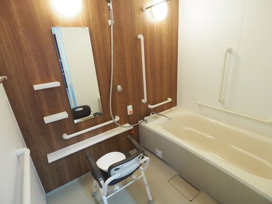 手すりや呼び出しボタンが設置された浴室には、シャワーも付き、大きな鏡がある。