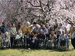 お花見に出かけた時の集合写真。満開の桜をバックに笑顔でカメラに向かってポーズを決めている。