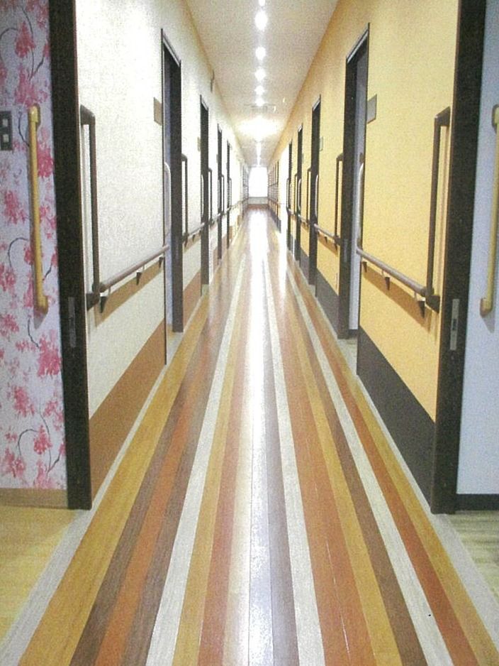スロライプのラインがひかれている施設の廊下。両側に手すりと個室のドアがある