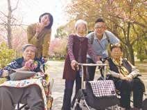 車いすに乗っている高齢者とそれを押している人。外に出てリラックスしている様子