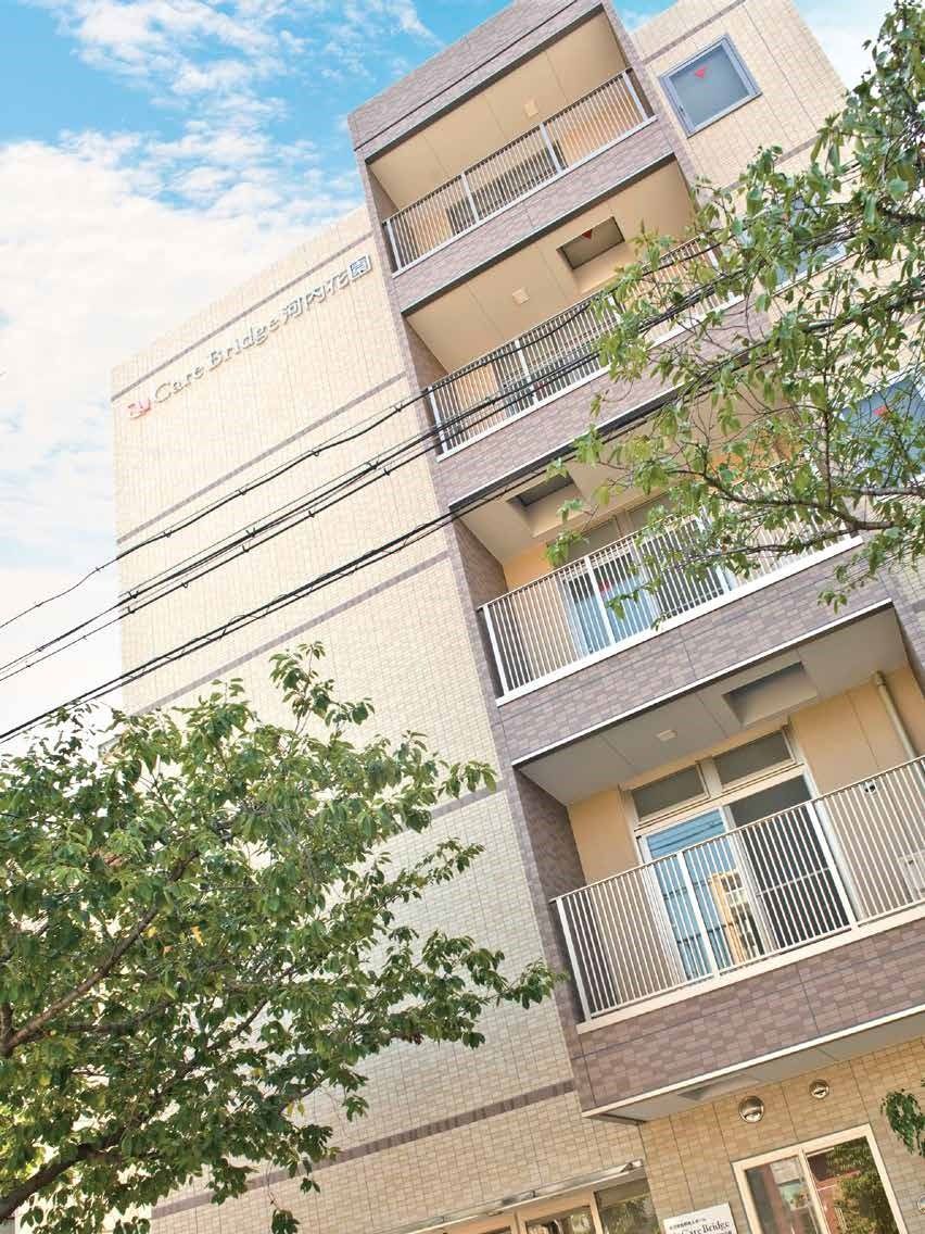 縦長の建物の外観。和らいベージュのような色合いの建物が写っている写真
