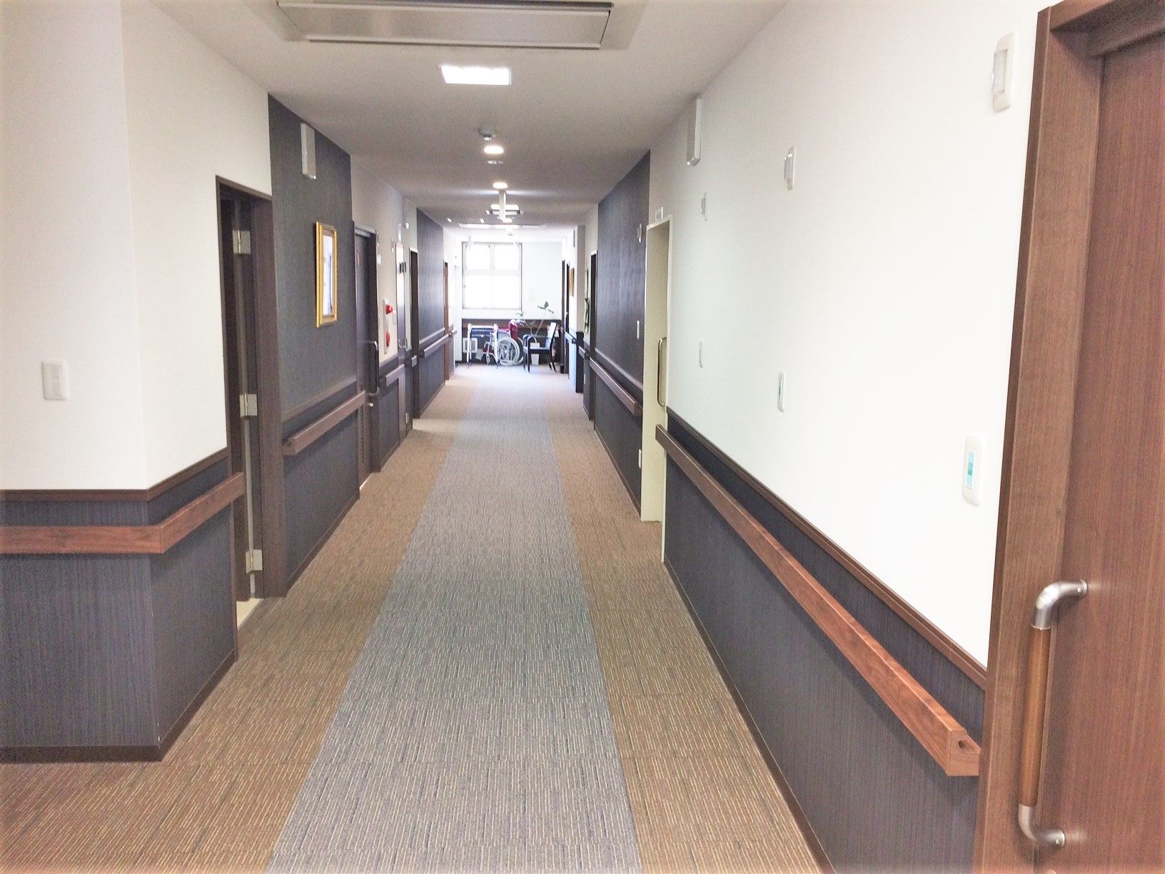 廊下はまっすぐで奥には窓があり、両サイドに手すりが設置されている。