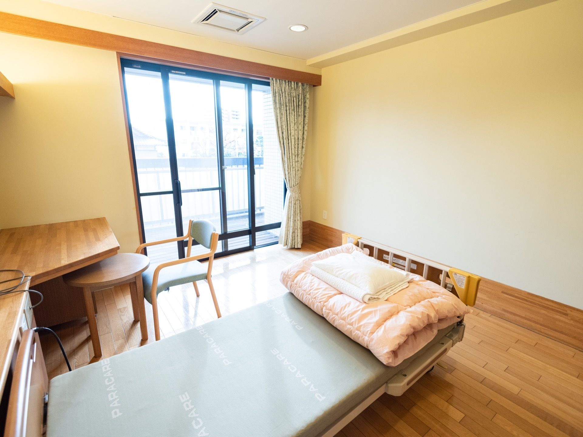 木のぬくもり感ただよう、居室である。広々とした掃き出し窓がある。ベッドも完備されている。