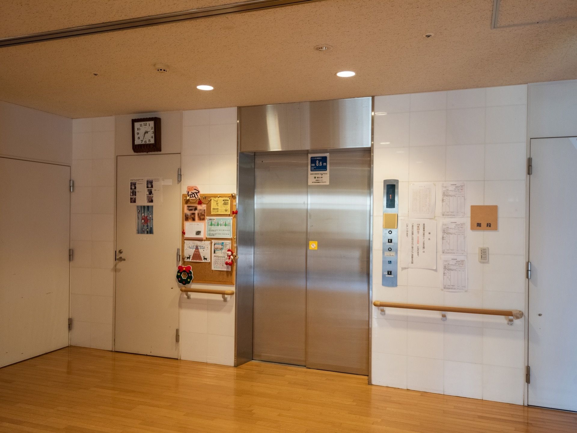 エレベーターが設置されている。出入口の両側に手すりがある。コルクボードには、さまざまな掲示板が貼られている。