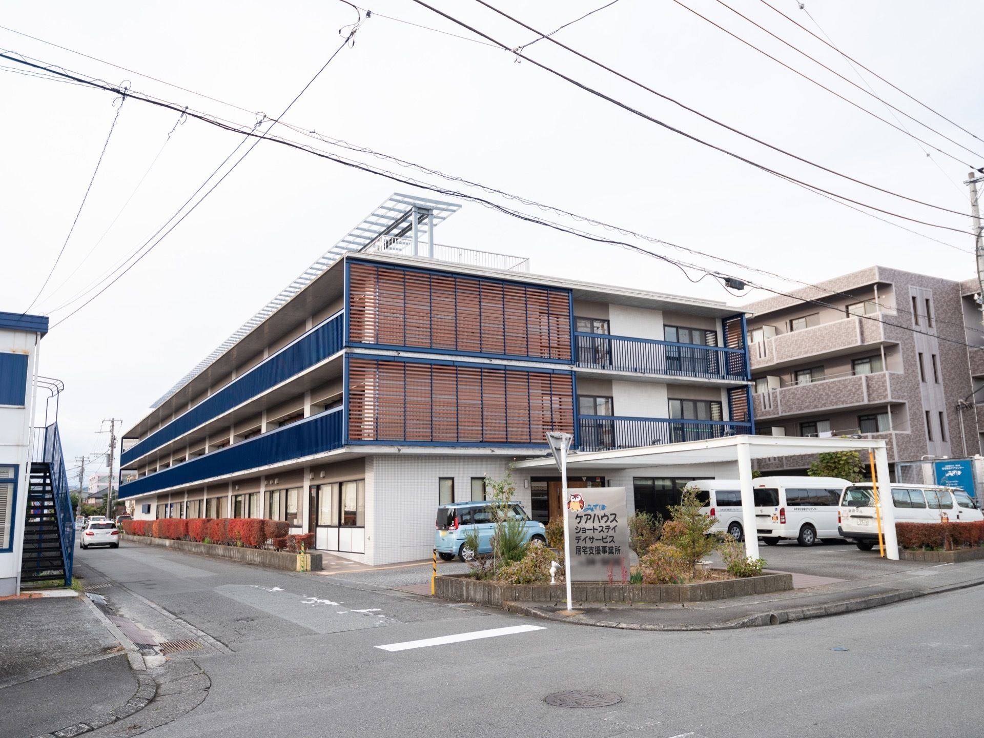 白色を基調とした、３階建ての施設である。ベランダはブルーにデザインされている。まわりは住宅地である。