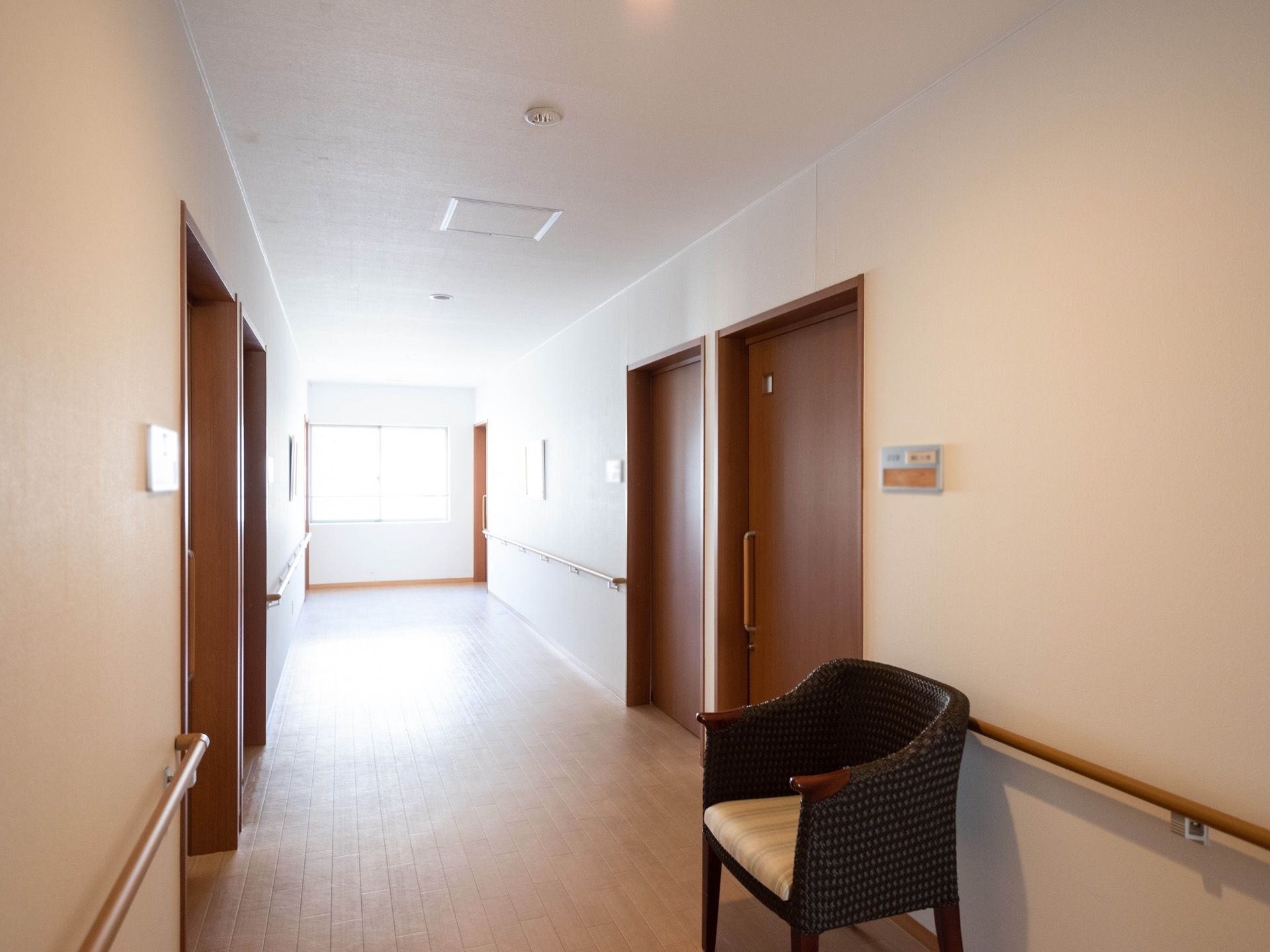 手すりが壁伝いに、備え付けられた通路である。突き当りに窓があり、自然光がさんさんと降りそそいでいる。